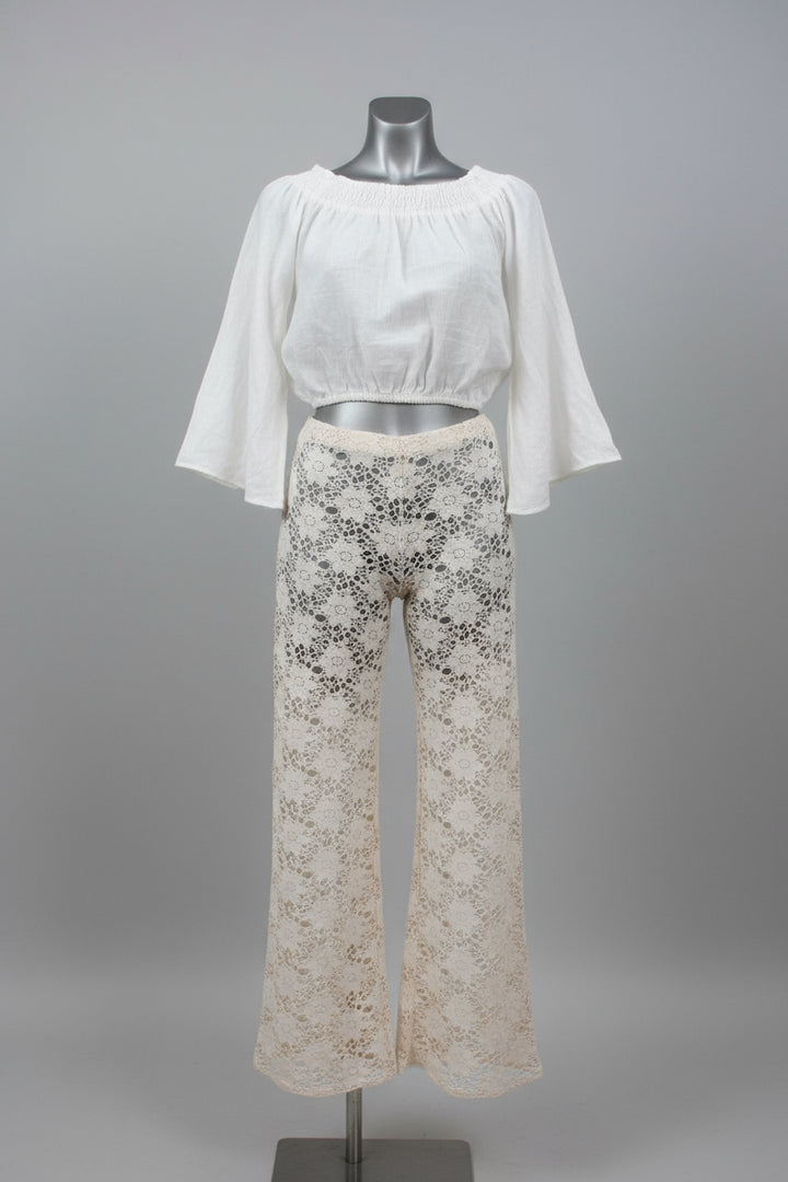 A two-piece women's outfit displayed on a mannequin against a gray studio background. The set includes a white off-the-shoulder short-sleeve crop top and off-white lace wide-leg pants with black floral embroidery.